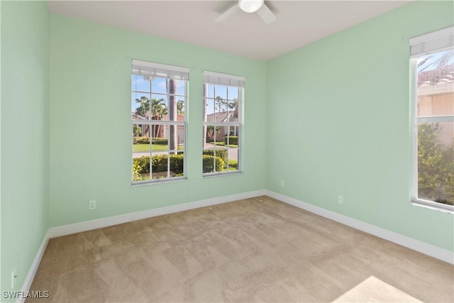 carpeted spare room featuring plenty of natural light and ceiling fan