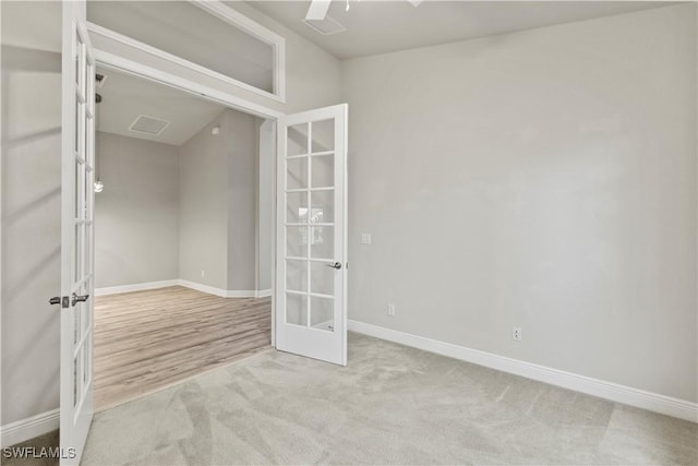 empty room featuring french doors and light carpet