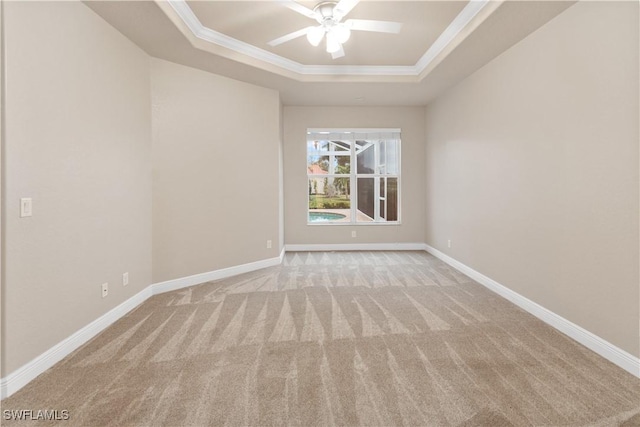 unfurnished room with ornamental molding, light colored carpet, ceiling fan, and a tray ceiling