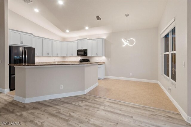 kitchen featuring lofted ceiling, hanging light fixtures, a center island, white cabinets, and stainless steel fridge with ice dispenser