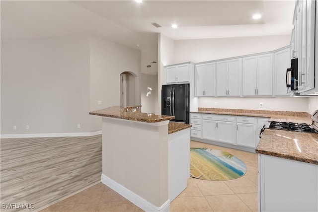 kitchen with white cabinetry, black appliances, and dark stone counters