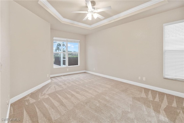 carpeted spare room with a raised ceiling, ornamental molding, and ceiling fan