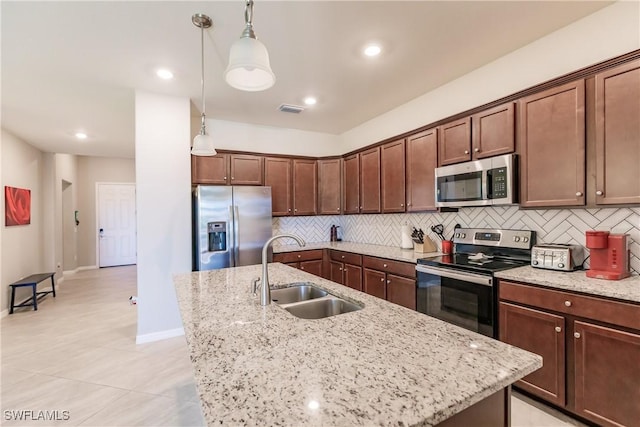 kitchen with appliances with stainless steel finishes, hanging light fixtures, light stone countertops, and sink