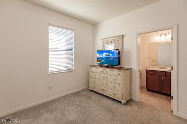 carpeted bedroom with ensuite bath and sink