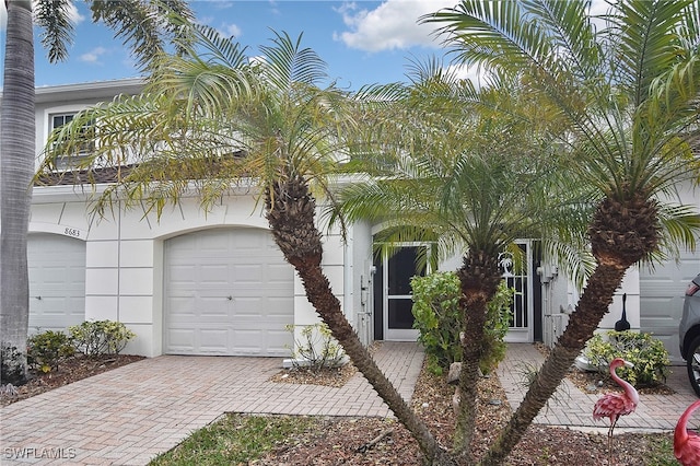 8681 Athena Ct, Lehigh Acres, FL 33971 - view of property hidden behind natural elements featuring decorative driveway and stucco siding