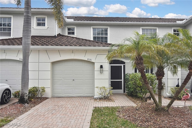 8681 Athena Ct, Lehigh Acres, FL 33971 - view of property featuring decorative driveway, a tile roof, a garage, and stucco siding