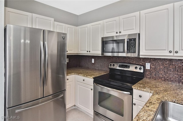 8681 Athena Ct, Lehigh Acres, FL 33971 - kitchen with appliances with stainless steel finishes, white cabinets, and backsplash