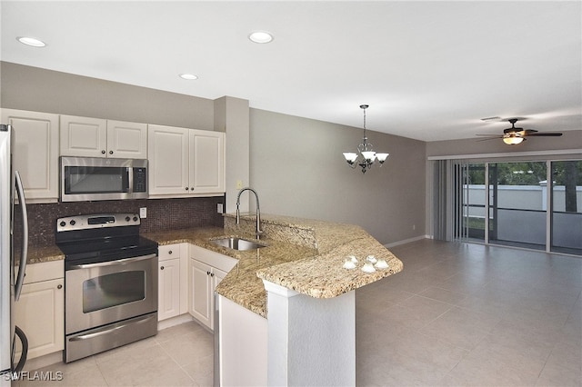 kitchen featuring decorative backsplash, appliances with stainless steel finishes, a peninsula, pendant lighting, and a sink