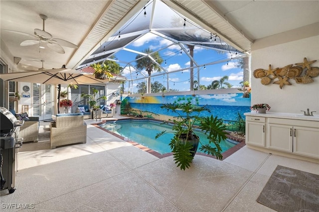 view of pool with an outdoor kitchen, a lanai, a patio, and ceiling fan