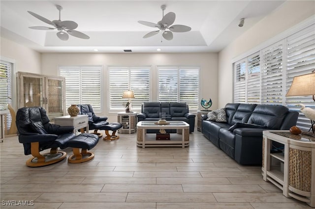 living room featuring ceiling fan and a raised ceiling