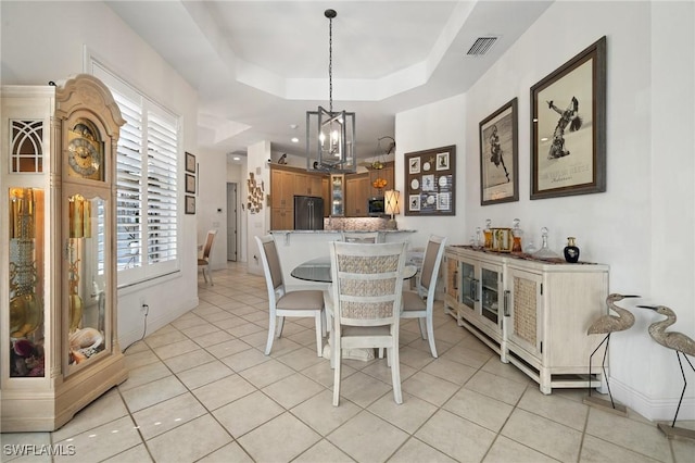 tiled dining room featuring a chandelier and a tray ceiling