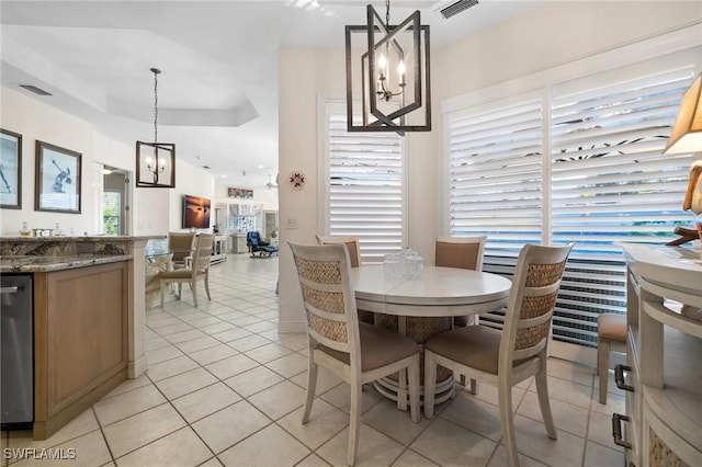 tiled dining room featuring a raised ceiling and a chandelier