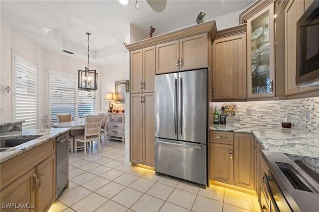 kitchen featuring light stone countertops, hanging light fixtures, light tile patterned floors, tasteful backsplash, and appliances with stainless steel finishes