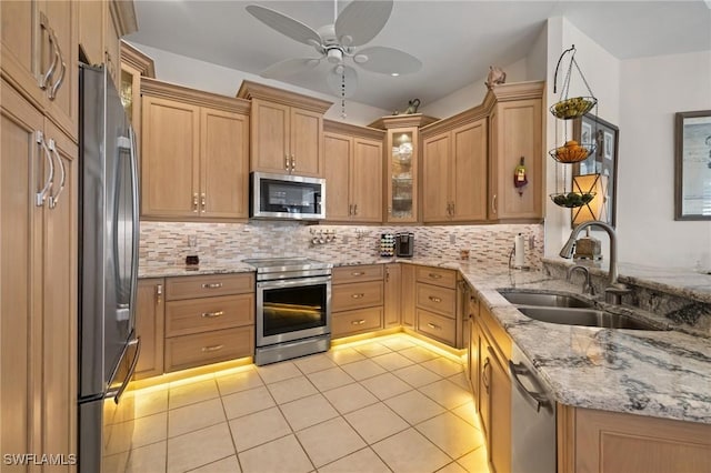 kitchen featuring appliances with stainless steel finishes, light stone countertops, ceiling fan, decorative backsplash, and sink