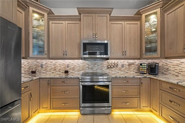 kitchen featuring appliances with stainless steel finishes, light stone countertops, light tile patterned flooring, and tasteful backsplash