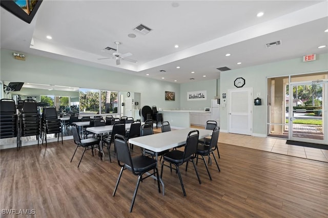 dining room featuring wood-type flooring, a raised ceiling, and plenty of natural light