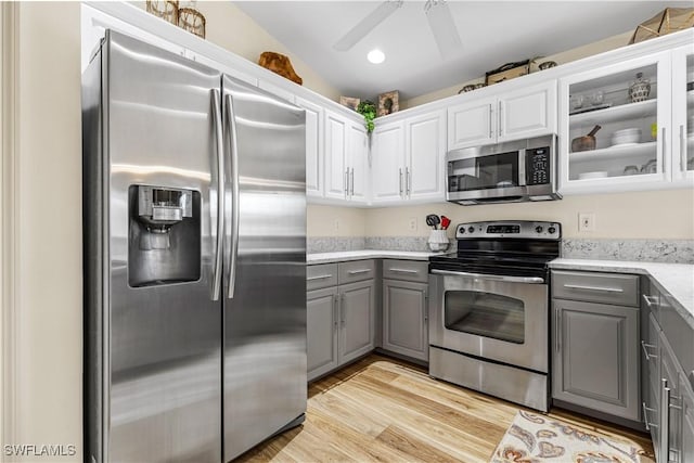 kitchen featuring vaulted ceiling, gray cabinets, light wood-type flooring, stainless steel appliances, and white cabinets