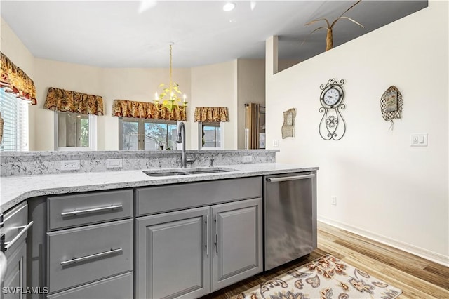 kitchen featuring dishwasher, light hardwood / wood-style floors, sink, a chandelier, and gray cabinetry