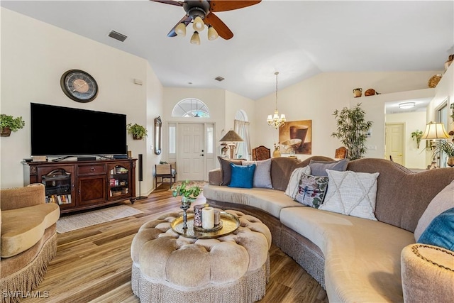 living room with vaulted ceiling, ceiling fan with notable chandelier, and light hardwood / wood-style flooring