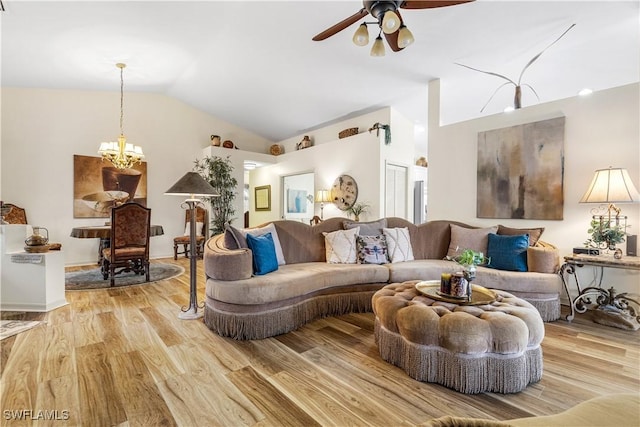 living room featuring vaulted ceiling, ceiling fan with notable chandelier, and light hardwood / wood-style flooring