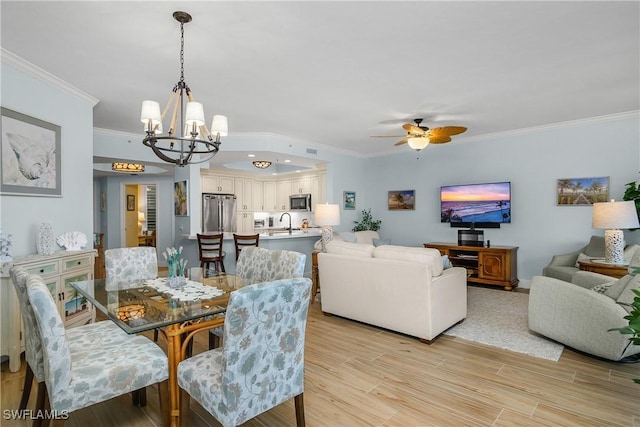 dining area featuring sink, ceiling fan with notable chandelier, light hardwood / wood-style flooring, and ornamental molding