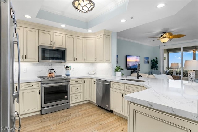 kitchen with appliances with stainless steel finishes, sink, cream cabinetry, tasteful backsplash, and ornamental molding