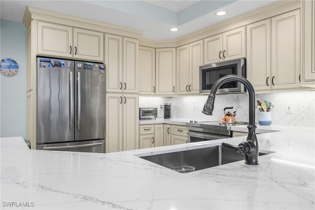 kitchen featuring stainless steel appliances, backsplash, and cream cabinets