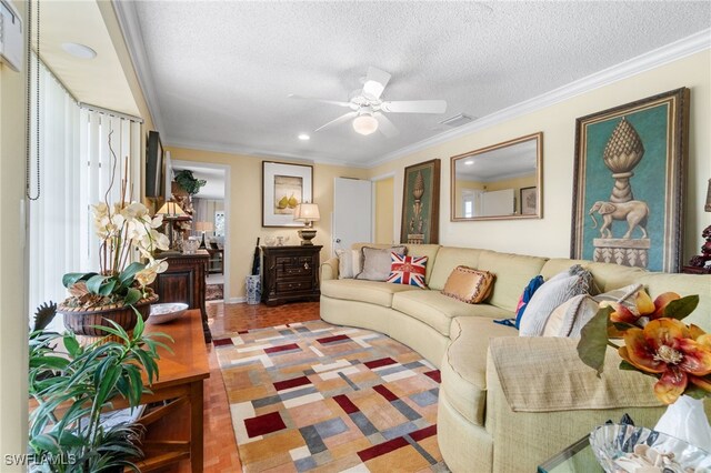 living room featuring ceiling fan, ornamental molding, and a textured ceiling