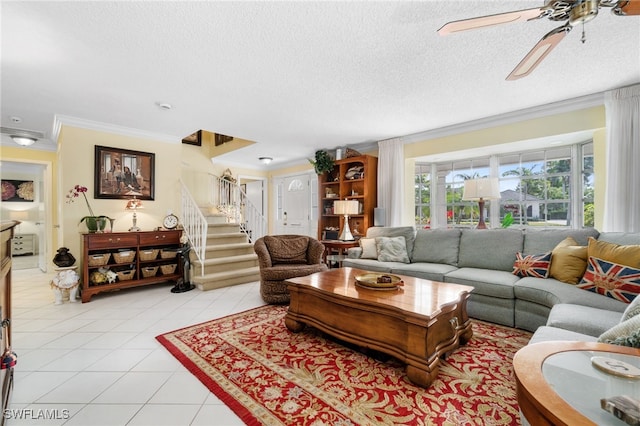 living room featuring light tile patterned floors, ornamental molding, a textured ceiling, and ceiling fan