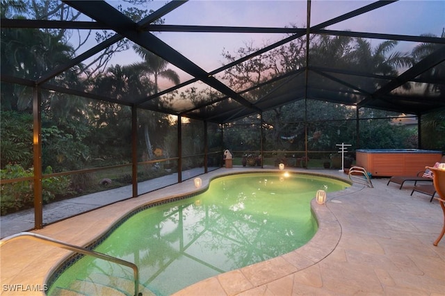 pool at dusk featuring a hot tub, a patio, and glass enclosure