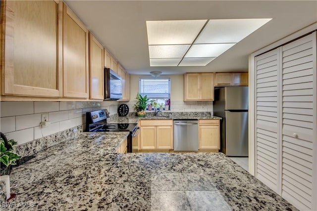 kitchen with appliances with stainless steel finishes, light brown cabinetry, sink, decorative backsplash, and light stone counters