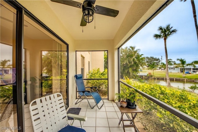 sunroom featuring ceiling fan and a water view