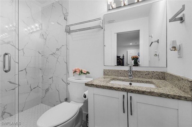 bathroom featuring a shower with door, vanity, and toilet