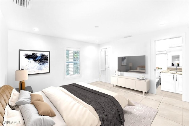 bedroom with connected bathroom, sink, and light tile patterned floors