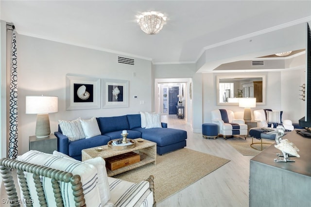 living room featuring a chandelier, crown molding, and light hardwood / wood-style flooring