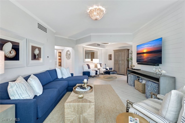 living room with light wood-type flooring, crown molding, and a chandelier