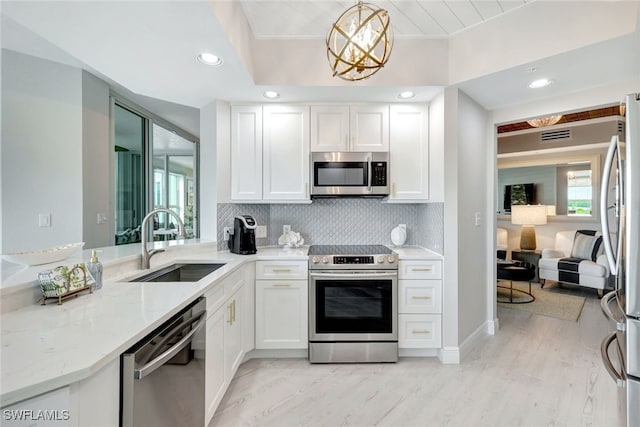 kitchen with decorative light fixtures, sink, plenty of natural light, stainless steel appliances, and white cabinets