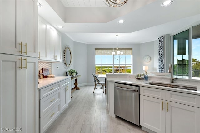 kitchen with stainless steel dishwasher, sink, an inviting chandelier, white cabinetry, and hanging light fixtures