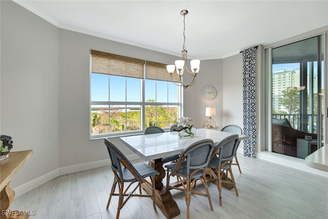 dining room with ornamental molding, light hardwood / wood-style floors, and a notable chandelier