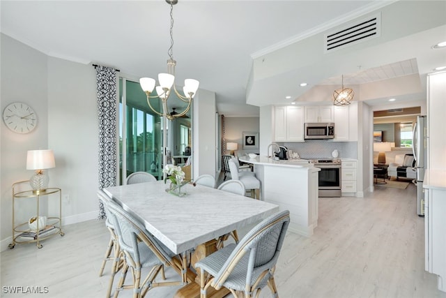 dining area featuring sink, light wood-type flooring, and an inviting chandelier