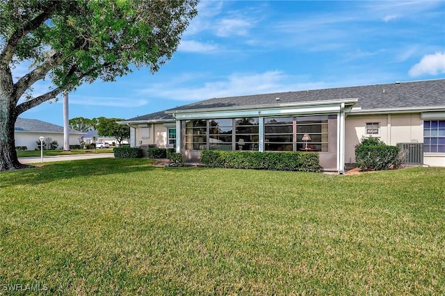 rear view of property featuring a yard and central AC