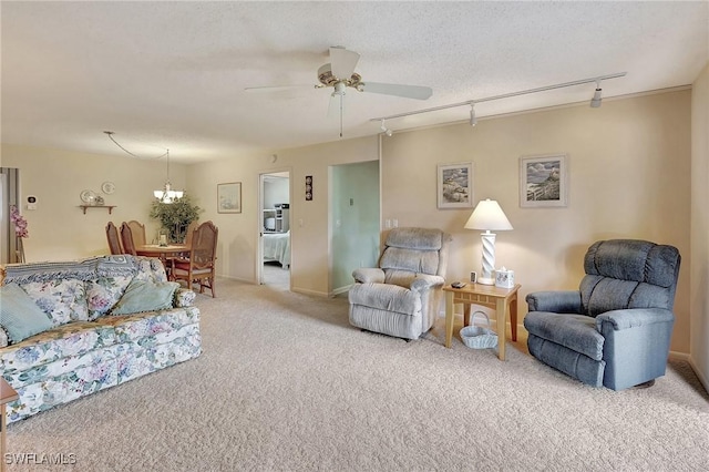 living room with rail lighting, ceiling fan with notable chandelier, a textured ceiling, and light carpet