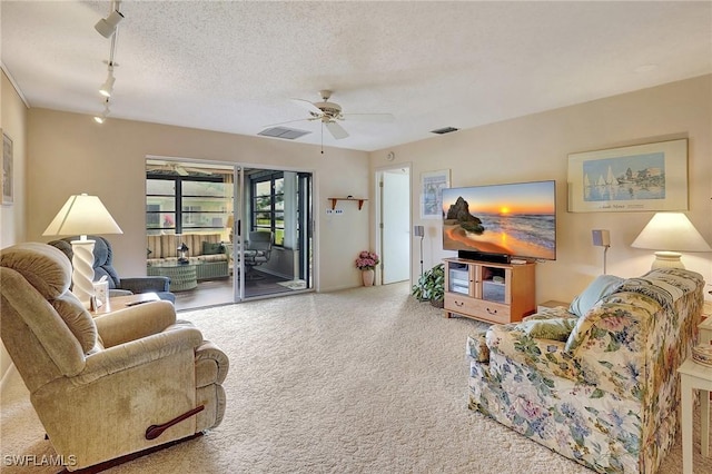 living room with track lighting, ceiling fan, and a textured ceiling