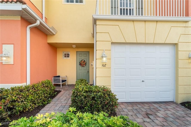 doorway to property with a garage and stucco siding