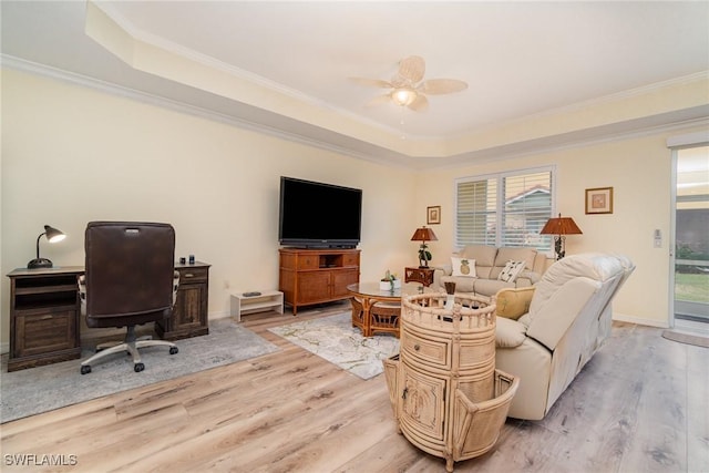 living room featuring ornamental molding, light hardwood / wood-style flooring, and a tray ceiling