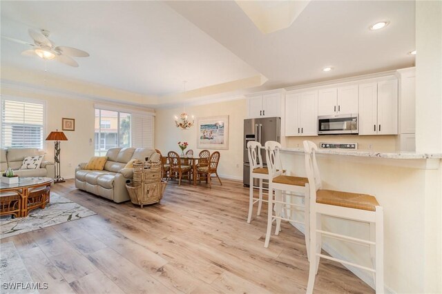16129 Via Solera Cir Unit 102, Fort Myers, FL 33908 - living room with recessed lighting, light wood finished floors, a raised ceiling, baseboards, and ceiling fan with notable chandelier