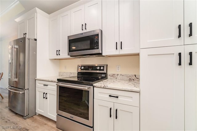 kitchen featuring light hardwood / wood-style floors, light stone counters, stainless steel appliances, and white cabinetry