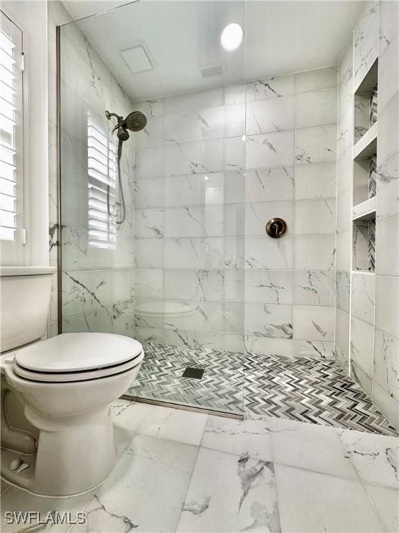 bathroom with toilet and tiled shower