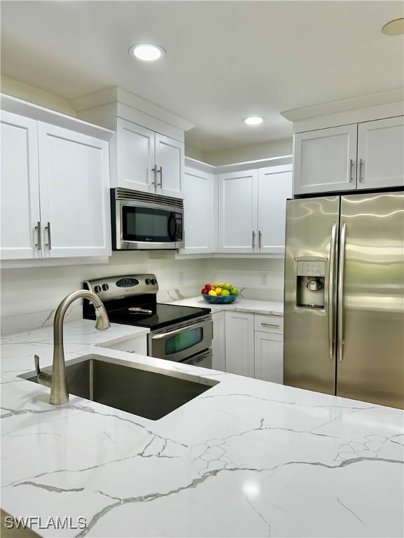 9553 Campbell Cir, Naples, FL 34109 - kitchen with white cabinetry, a sink, and stainless steel appliances