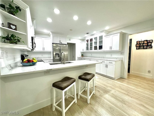 9553 Campbell Cir, Naples, FL 34109 - kitchen with a peninsula, light wood finished floors, appliances with stainless steel finishes, glass insert cabinets, and a sink